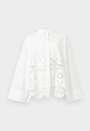 Λευκό πουκάμισο με μακριά μανίκια και γιακά με κουμπιά, με μοτίβο από λουλουδάτη δαντέλα και κοψίματα στο κάτω μέρος και το τελείωμα.