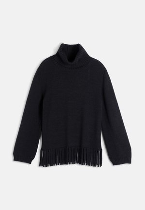 Femme portant un ensemble pull à franges et jupe noirs, large ceinture noire, bottes noires montant jusqu'au genou, tenant un sac à main noir avec une boucle dorée.