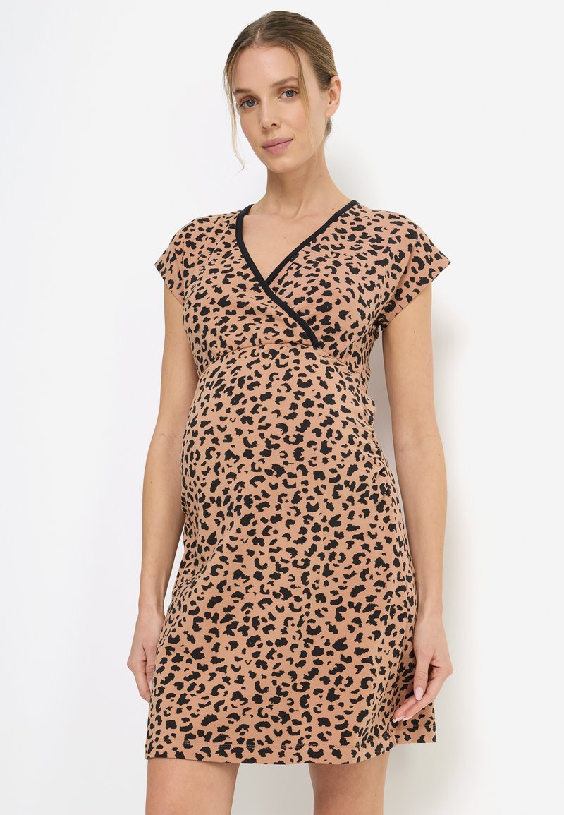 Ένδυμα εγκυμοσύνης σε απαλό, ελαστικό ύφασμα με σχέδιο λεοπάρ σε καφέ πάνω σε μπεζ φόντο, με κοντά μανίκια καπελάκι και μαύρη επένδυση.