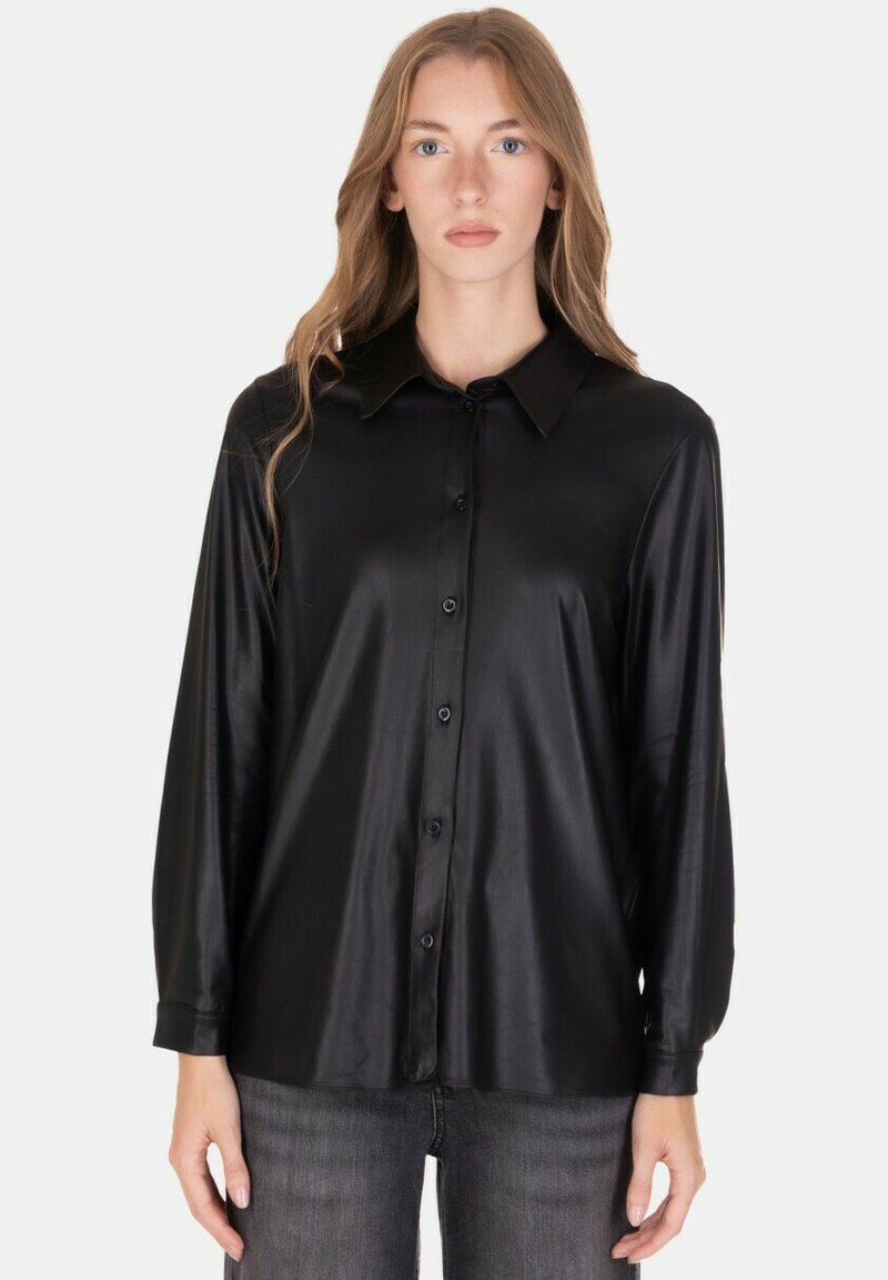 Camicia nera leggera con trama liscia, maniche lunghe, chiusura frontale con bottoni e colletto classico, abbinata a jeans scuri.