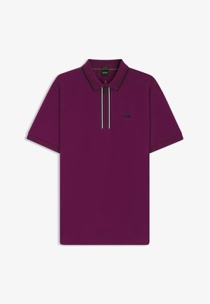Polo shirt violet à manches courtes, avec un zip sur le col, logo noir et détails rayés contrastants sur la fermeture éclair. Texture lisse et coupe moderne.