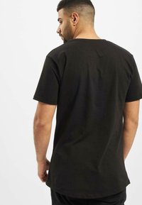 Zwarte katoenen T-shirt met korte mouwen en een ronde zoom, met een eenvoudig ontwerp en een subtiele naaddetail aan de achterkant.