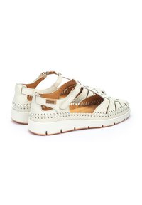 Sandalias de cuero blanco con diseño de recortes, detalles de costura, correas ajustables y suela acolchada para mayor comodidad. Presenta una suela de goma.