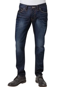 Mörkblå jeans i denim med rak ben skärning, med sydda detaljer, femficksdesign och knappgylf. Bärs med grå skor.