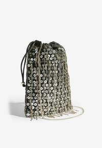 Fekete húzózsinóros táska ezüst flitterekkel és láncokkal díszítve. A táska hosszú bojtokkal és sima szövettextúrával rendelkezik. Könnyű és kompakt.