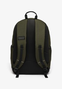 Mochila Superdry Outdoor en verde oscuro y negro con correas acolchadas y panel trasero de malla, vista desde la parte trasera.