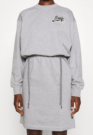Graues Sweatshirtkleid mit langen Ärmeln, Kordelzug in der Taille und "Boss"-Logo auf der linken Brust, getragen von einer Person mit dunklem Hauttyp.