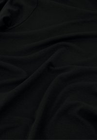 Zwart katoenen stof met een zachte, gladde textuur, voorzien van zachte plooien en schaduwen die de val en het gewicht benadrukken.