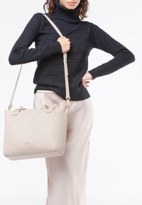 Borsa a tracolla in pelle beige chiaro con una finitura testurizzata, dotata di impreziositure in tonalità oro, doppi manici superiori e una tracolla removibile.