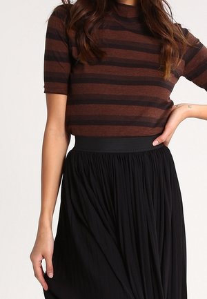 Top de manga corta de rayas marrones y negras combinado con una falda plisada negra, que cuenta con una amplia cinturilla elástica y un tejido fluido.