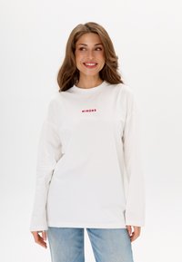 Witte longsleeve shirt met ronde hals, voorzien van rode geborduurde tekst "MIRONS" op de borst. Zachte stof en een casual pasvorm.
