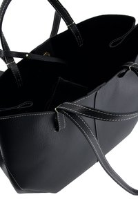 Black leather tote bag with a textured finish, contrasting white stitching, and long handles. Open top design allows for easy access.