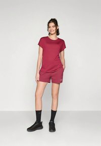 Bordeauxrood T-shirt met korte mouwen en bijpassende bordeauxrode korte broek. Zwarte sneakers en zwarte sokken maken de outfit compleet. Eenvoudig en casual ontwerp.