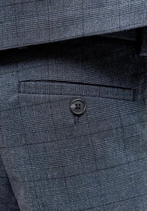 Mørkeblå mønstret stof med et lille ternet design. Har en indsyet lomme og en sort knapdetalje på siden.