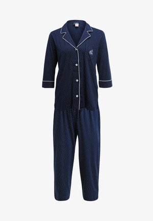 Mørkeblå pysjamassett med hvite prikker og piping, som har en knappe-ned topp med 3/4 ermer og elastisk midje på capribukser.