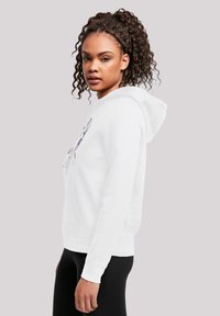 Hvit hettegenser med frontlomme og snøring i hetta. Har et enkelt grafisk trykk i lilla. Modellen har på seg svarte tights.
