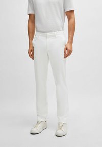 Vita skräddarsydda byxor med rak passform, tillverkade av mjukt tyg, med sidofickor och dragkedja. Bärs med vita sneakers.