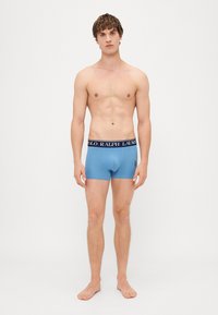 Boxerii scurți albaștri dintr-un material fin, cu un brâu negru pe care este brodat textul și logo-ul "POLO RALPH LAUREN" pe partea stângă.