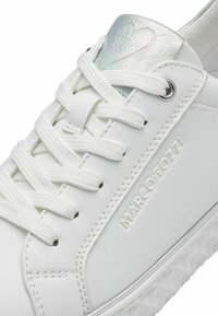 Sneaker bianco con tomaia testurizzata, dotata di lacci piatti e un accento del tallone olografico. "Marco Tozzi" embossato di lato. Suola in gomma.