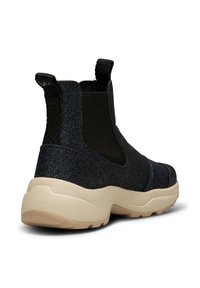 Botas de tobillo negras y brillantes con una gruesa suela en color crema y paneles laterales texturizados. Incluyen tiradores para facilitar su colocación.
