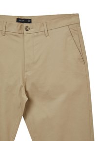Pantaloni in cotone beige con una texture liscia, dotati di chiusura con un solo bottone, passanti per cintura e tasche laterali. L'etichetta riporta 'CALLIOPE'.