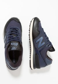 Marineblaue Sportsneaker aus einer Mischung aus Leder und Mesh, mit einer strukturierten Oberfläche, hellgrauen Akzenten und einer schwarzen Gummisohle.