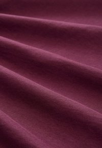 Tissu prune foncé avec une texture douce, présentant des plis délicats et une finition lisse, affichant une couleur uniforme sans motifs ni accents.