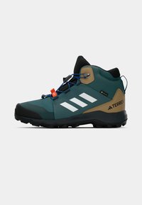 Botas de caminhada impermeáveis em verde azulado escuro e castanho, com riscas refletivas brancas, detalhes em preto e uma sola de borracha texturizada.