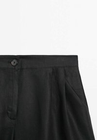 Pantalons en lin noir à taille haute, dotés d'une fermeture à bouton simple et de plis à l'avant. Texture lisse et légère.