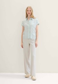 Light blue and white striped short-sleeve shirt with button closure, paired with light gray trousers and chunky beige shoes.
