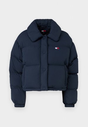 Marineblå puffjakke med kort design, stor krage, frontknapper og en liten logo med røde og hvite detaljer på brystet.