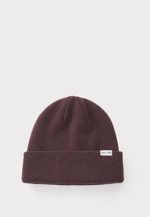 Knit beanie in dark burgundy, featuring a ribbed texture and folded cuff. Includes a small white brand tag on the side.