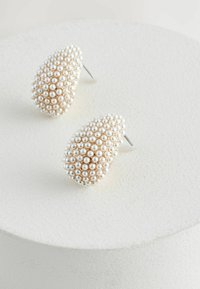 Orecchini a forma di goccia, adornati con perle bianche e un'elegante base in oro testurizzato, dotati di un perno in argento per il fissaggio.