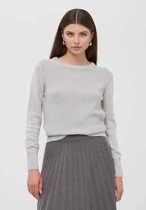 Maglione lavorato a maglia grigio chiaro con scollatura rotonda e maniche lunghe, abbinato a una gonna plissettata grigio scuro. Il tessuto presenta una finitura testurizzata.