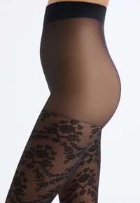 Collant neri con motivo, caratterizzati da una parte superiore trasparente e un design in pizzo floreale sulla parte inferiore della gamba. Texture liscia con una vita ampia.
