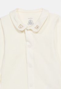 Βρεφικό ολοσωμο φορμάκι εκρού με μαλακό γιακά που διαθέτει δύο μικρά κεντημένα προσωπάκια αρκούδας και κουμπιά στο εμπρόσθιο μέρος.