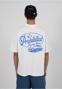 Valge t-särk sinise graafikaga, millel on kiri "Prohibited Racing Club" ja auto illustratsioon, lühikeste varrukatega ning lõdva istuvusega.