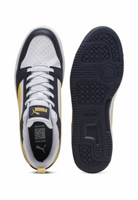 Puma sneakers med en øvre del i hvid og marineblå læder med gule accenter, perforeret design, flade snørebånd og en tekstureret gummisål.