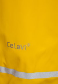 Gele regenjas met een gladde textuur, reflecterende zilveren streep en Celavi®-branding in zilver. Duurzaam materiaal dat geschikt is voor nat weer.