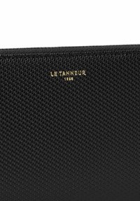 Portafoglio nero texturizzato con motivo intrecciato, caratterizzato da un logo dorato in rilievo "LE TANNEUR" sopra l'anno "1888."