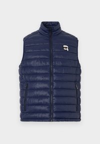 Mørkeblå, quiltet, ermeløs vest med glidelås foran, to lommer med glidelås og en liten logo med en figur som har på seg solbriller.