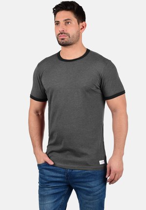 Gray short-sleeve t-shirt with black ribbed collar and cuffs, featuring a straight cut and side tag detail, worn with blue jeans.