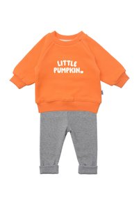 Oranger Pullover mit weißem "LITTLE PUMPKIN"-Text, kombiniert mit grauen Baumwollhosen mit umgeschlagenen Säumen. Weiches Material, lässige Passform.