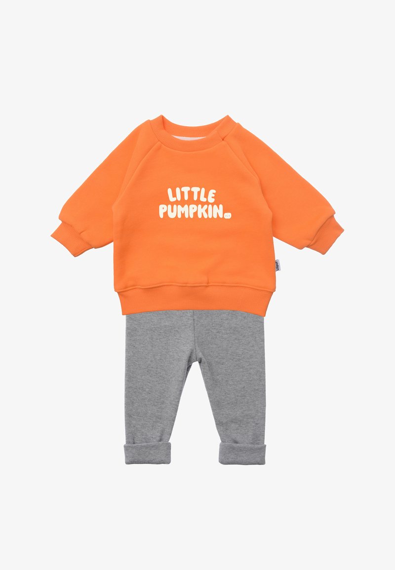 Oranger Pullover mit weißem "LITTLE PUMPKIN"-Text, kombiniert mit grauen Baumwollhosen mit umgeschlagenen Säumen. Weiches Material, lässige Passform.