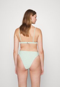 Maiô verde menta com padrão floral. Alças finas ajustáveis e detalhe canelado nas costas. Parte de baixo de cintura alta com cobertura moderada.