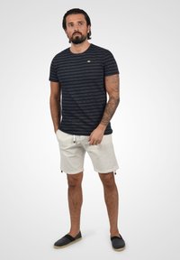 Marine gestreept T-shirt met korte mouwen. Lichtgekleurde shorts met trekkoord en zakaccenten. Zwarte schoenen met een casual ontwerp.