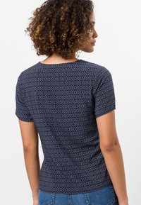 Camiseta navy de manga corta, con un patrón geométrico en azul claro. Corte normal, tela suave y cuello redondeado.