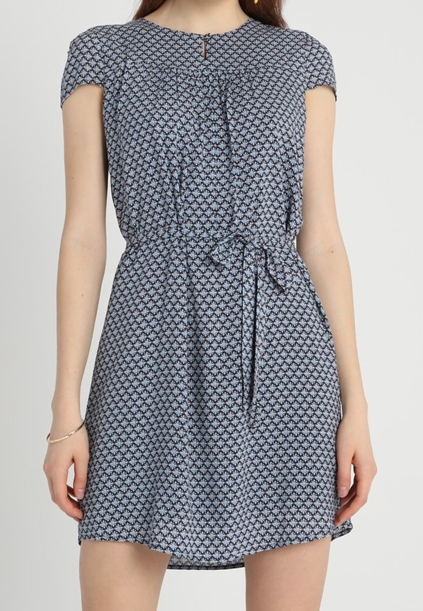 Robe à manches courtes avec une taille cintrée, présentant un motif floral bleu et blanc, un col arrondi, et une ceinture à nouer pour ajustement.