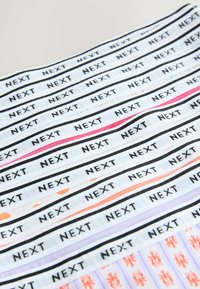 Des bandes de tissu disposées horizontalement, chacune avec un fond blanc, une bordure noire, et le texte "NEXT" répété en lettres majuscules noires, certaines avec des couleurs subtiles.