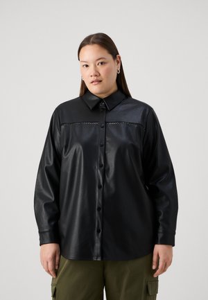Zwarte neplederen blouse met een knoopsluiting aan de voorkant, lange mouwen en een kraag. Beschikt over een gemêleerd horizontaal paneel over de borst.